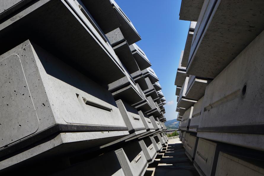 Concrete slabs stacked vertically against a blue sky, creating a narrow pathway between them.
