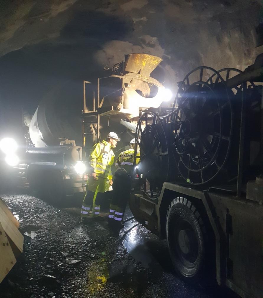 Fibre application in mines Two employees in mine between construction vehicles and lighting